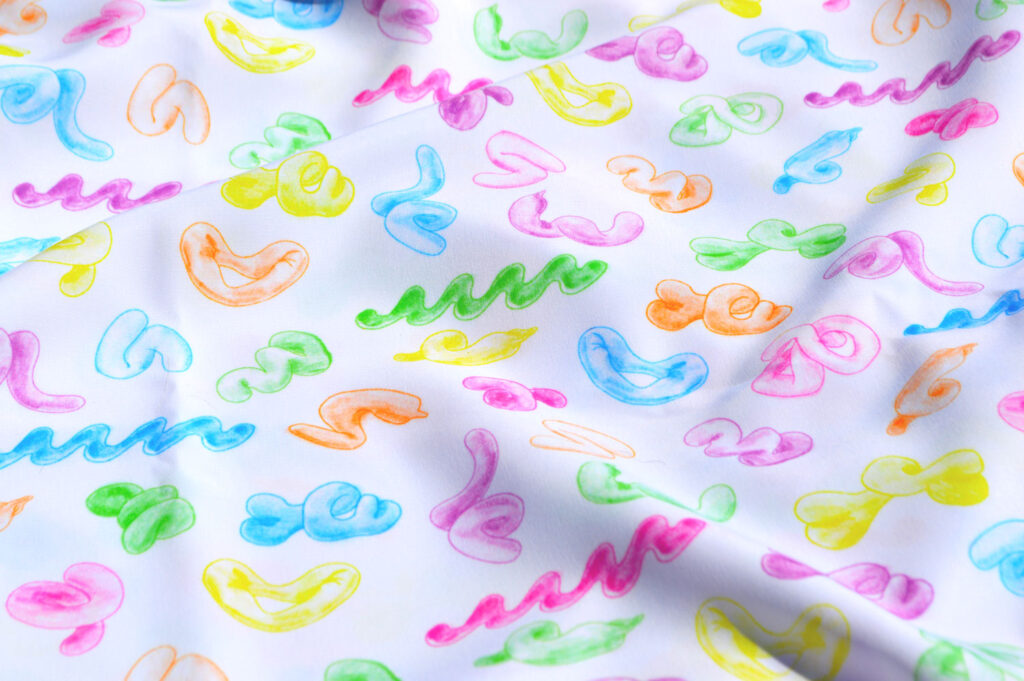 Fabric with a printed pattern of different colored abstract shapes. 