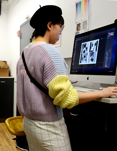 Student in sweater and black beret preparing her files for printing on the RisoLab computer