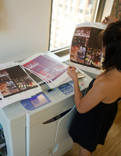 Student looking at different CMYK Print tests of photographs on top of a Risograph printer