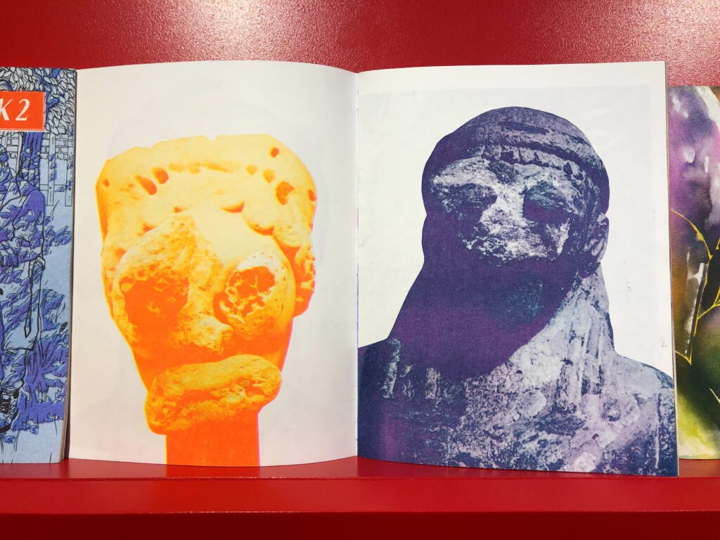 Photograph of an open spread from a riso zine, two duotone photo prints of sculptures, one is yellow-orange, the other is dark purple-green.