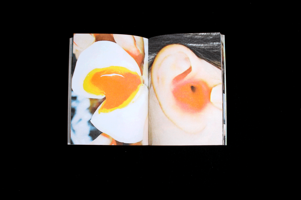 Open spread of a photo book, the left page shows a soft boiled egg being split in half, the right page shows a close up of an ear with a deep orange center.