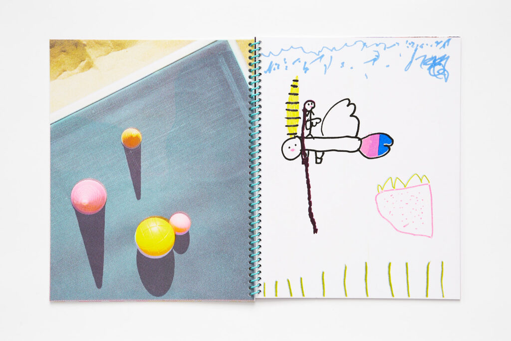 Double page spread, left image is a photograph of pink, yellow and orange balls on a teal woven fabric, right image is a child's drawing of a small figure with a long braid on top of a creature with wings, over a large strawberry.
