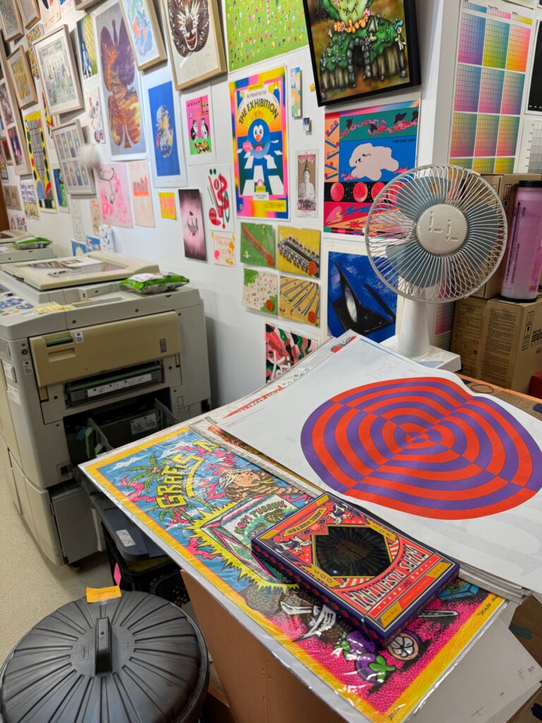 Colorful prints and a Riso machine in the background