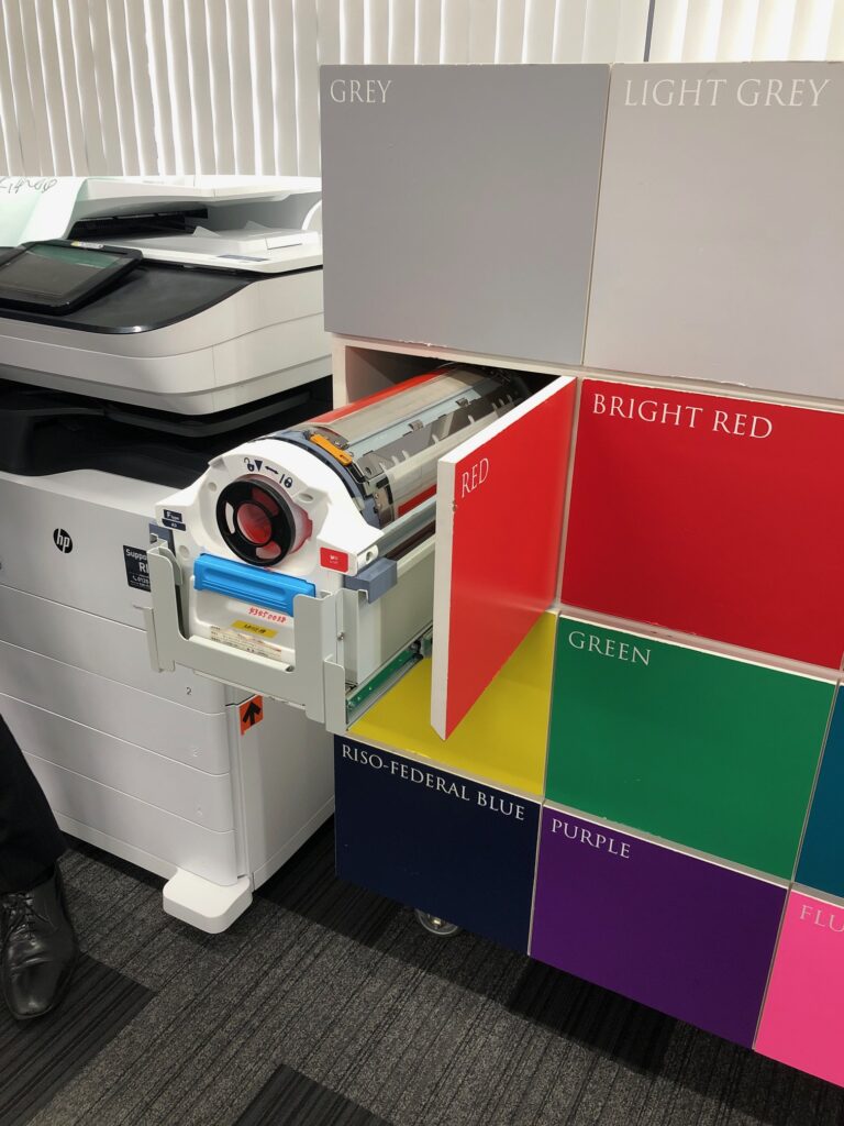 Closeup of a Riso drum emerging from a color coded cabinet