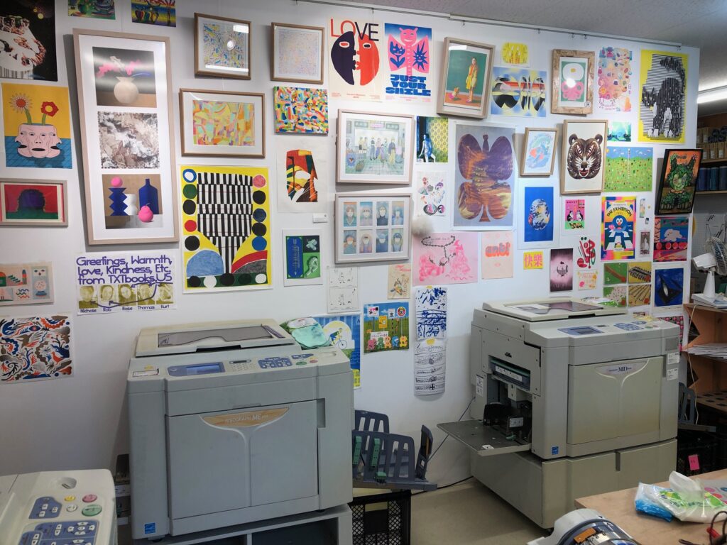 interior studio view, two Risograph duplicators, a wall of colorful prints