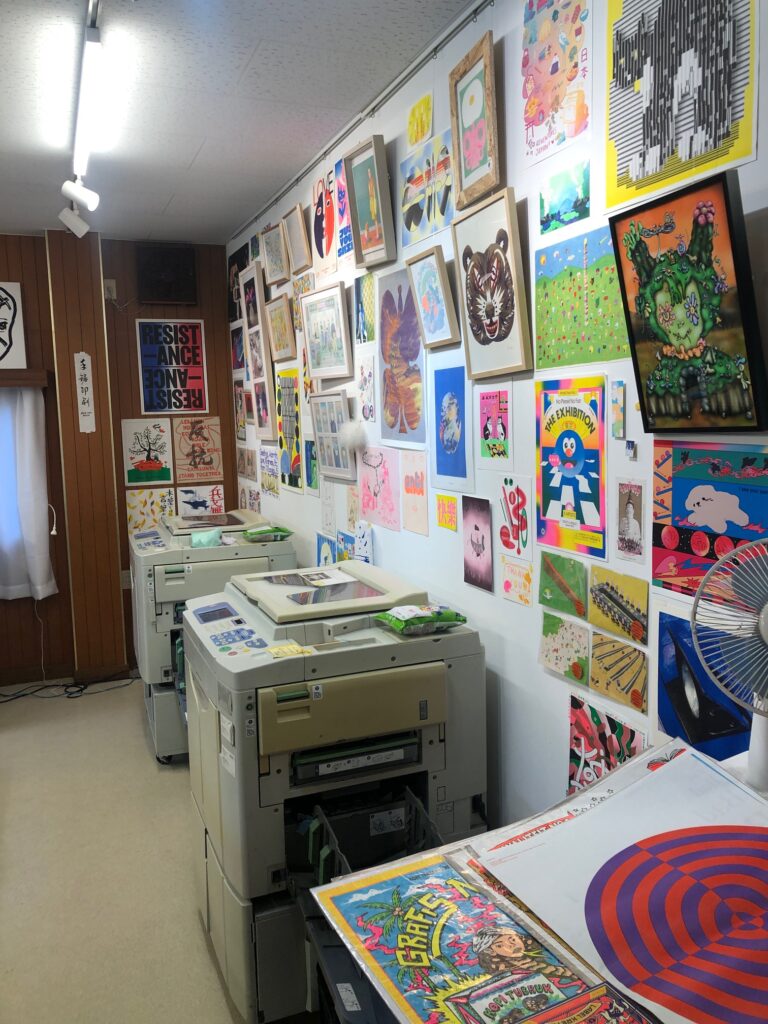 interior studio view, two Risograph duplicators, a wall of colorful prints