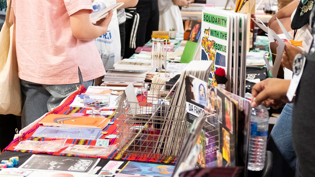 Tables full of stacks of zines on display, for sale at a fair.