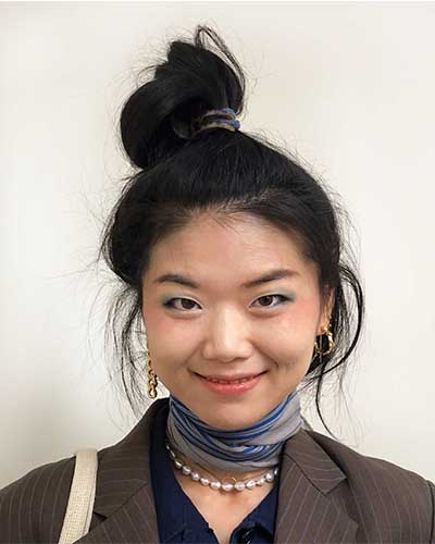 Smiling artist Yiran Guo with hair in a bun