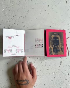 Open spread of Sarah Hakani Zarina's publication, an accordion book with a red cover containing two single pamphlets, one side with black and red geometric abstractions printed on white paper, the other side with gold abstractions printed on black paper.