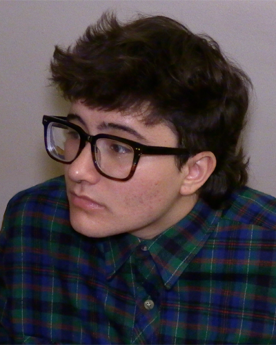 Headshot of Jean Doran, who has short brown hair, light skin and wears thick rimmed glasses and a plaid shirt.
