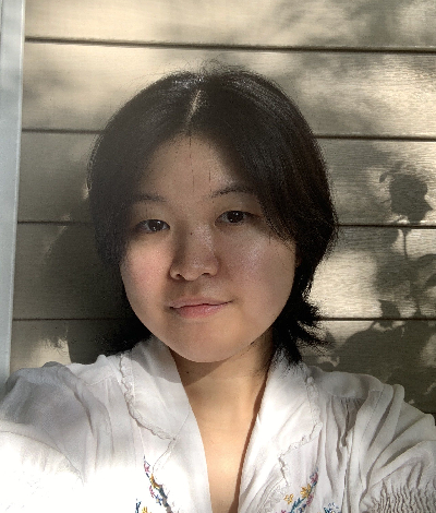 Photo of Anna Shimizu, she has short black hair with curtain bangs and wears a white shirt.